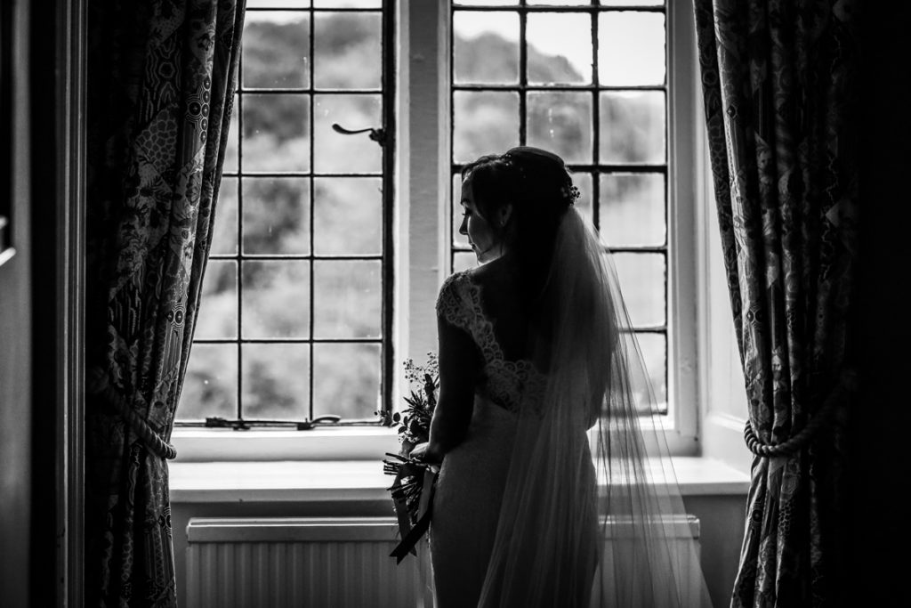 lake district documentary wedding photographer Askham Hall bride in a window black and white