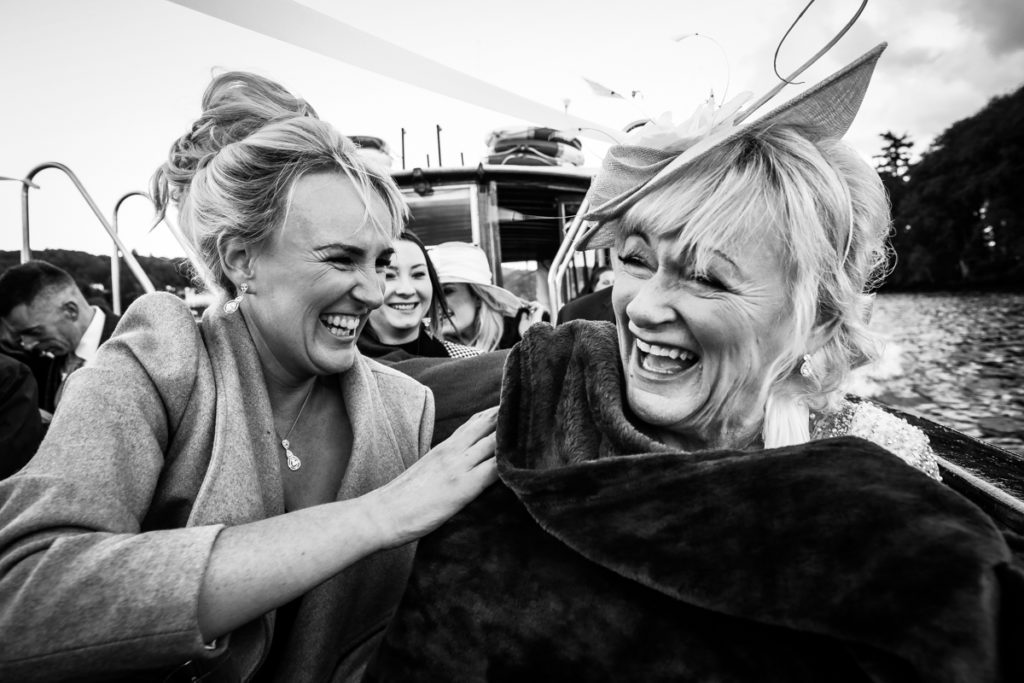 lake district documentary wedding photographer guests laughing on a boat