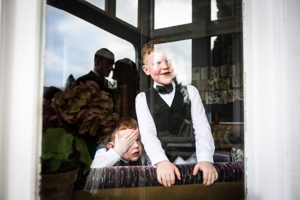 lake district documentary wedding photographer silhouette with children laughing at parents kissing in window