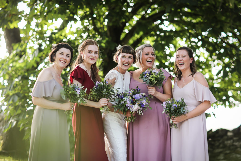 lake district documentary wedding photographer Bridesmaids laughing in front of trees