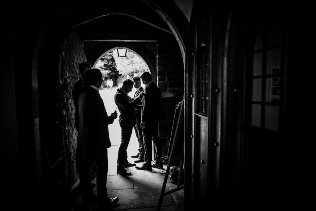 lake district documentary wedding photographer ushers and groom in the church door silhouette in black and white