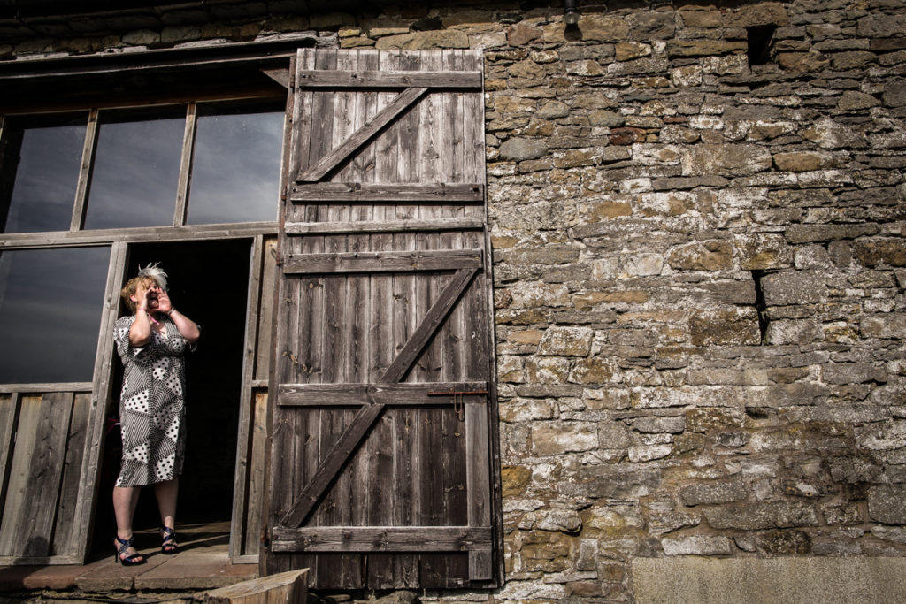 lake district documentary wedding photographer woman shouting in front of a barn