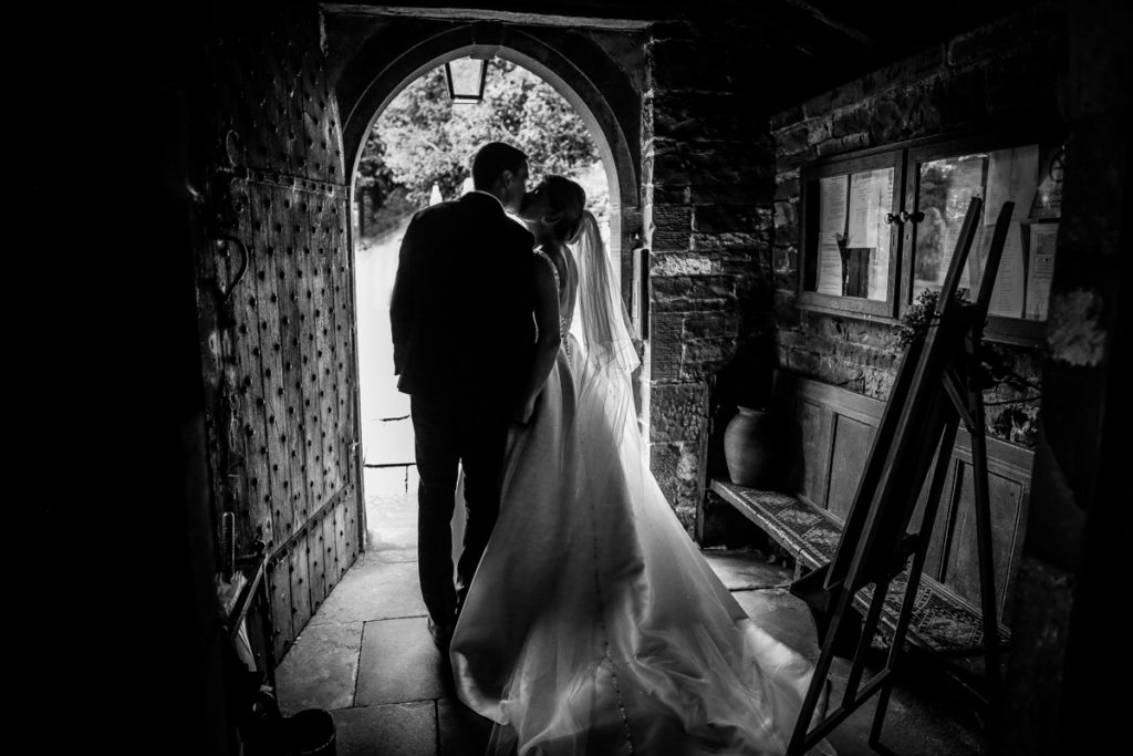 lake district documentary wedding photographer couple kissing in church door in black and white