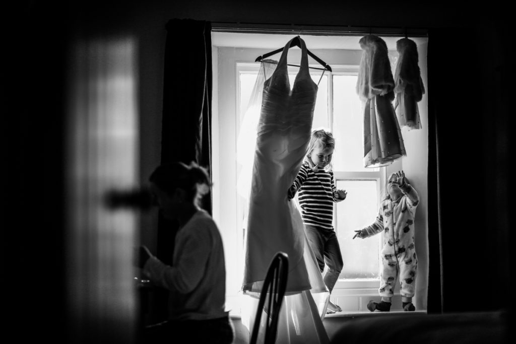 lake district documentary wedding photographer childresn playing with dress in window